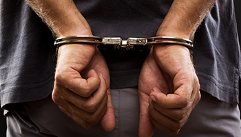 A person's hands are handcuffed behind their back.